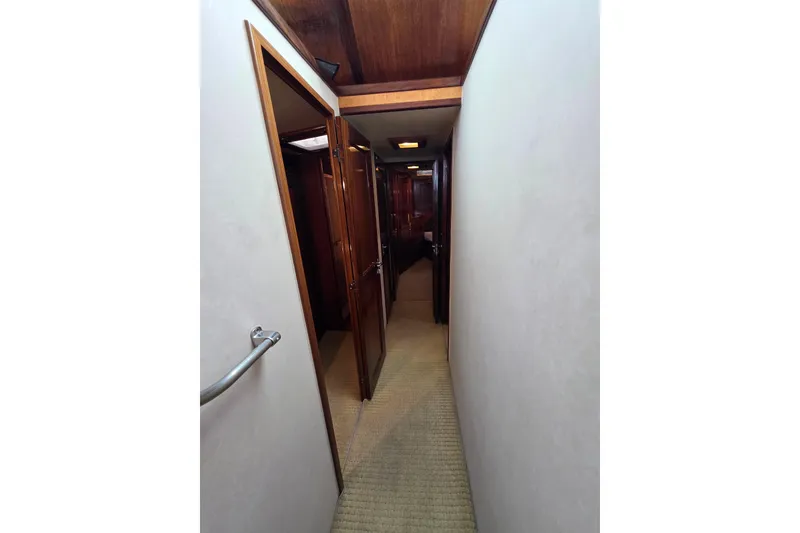 Slide: The Image of Narrow hallway inside 1987 Hatteras 52 Convertible yacht with wooden doors and carpeted floor. - 21