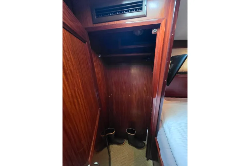 Slide: The Image of 1987 Hatteras 52 Convertible cabin closet with wooden finish and boots. - 24