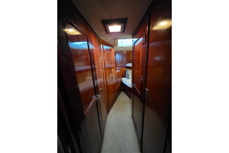 Slide: The Image of 1987 Hatteras 52 Convertible yacht interior hallway with wooden paneling and carpeted floor. - 32