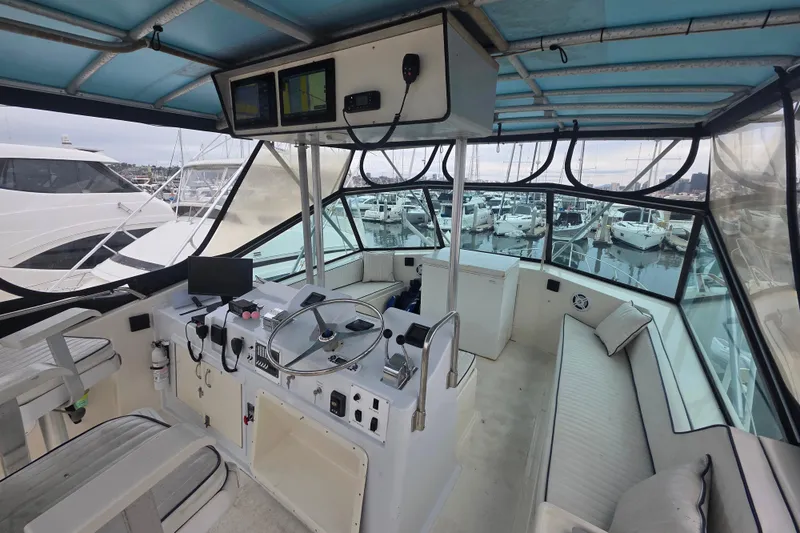 Slide: The Image of 1987 Hatteras 52 Convertible yacht interior with helm, marina view, and seating area. - 48