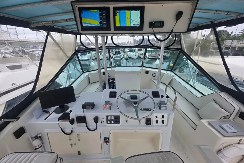 Slide: The Image of 1987 Hatteras 52 Convertible yacht cockpit with navigation equipment and marina view. - 49