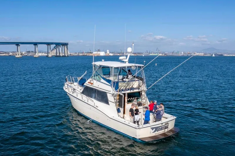 Slide: The Image of 1987 Hatteras 52 Convertible yacht cruising near a bridge on a sunny day. - 87