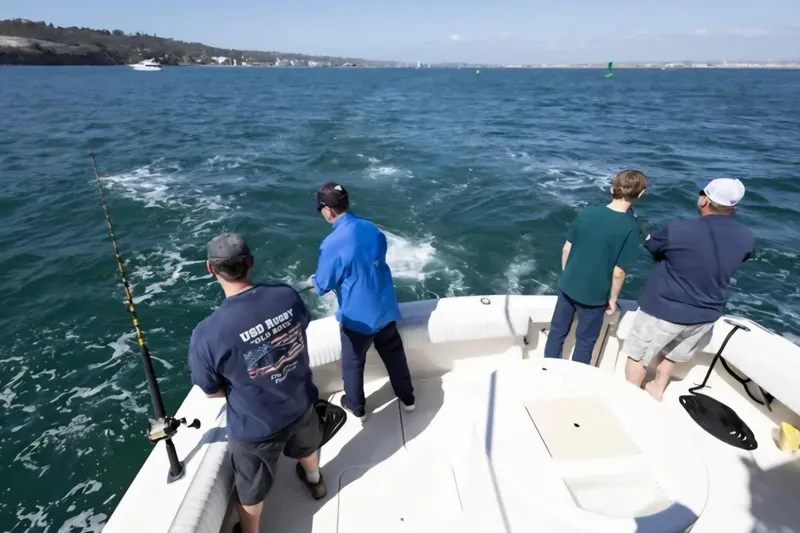Slide: The Image of Four people fishing on a 1987 Hatteras 52 Convertible boat in open water. - 92