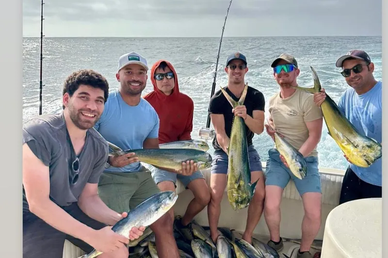 Slide: The Image of Group of men holding fish on a 1987 Hatteras 52 Convertible boat. - 93