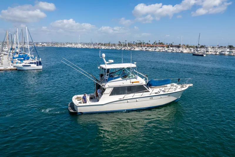 Slide: The Image of 1987 Hatteras 52 Convertible yacht cruising in a marina under a clear blue sky. - 94