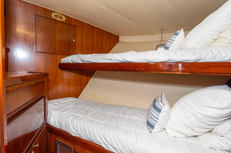 Slide: The Image of 1987 Hatteras 52 Convertible yacht cabin with wooden bunk beds and white bedding. - 95