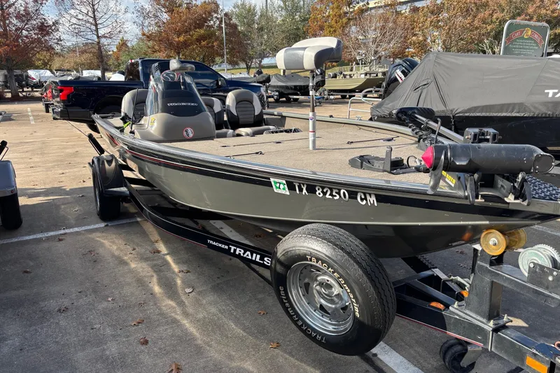 Slide: The Image of 2005 Bass Tracker V18 boat on trailer in parking lot, surrounded by autumn trees. - 8