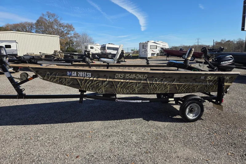 The Image of 2018 SeaArk DXS 1548 DKLD boat on trailer, camo design, parked outdoors. - 0