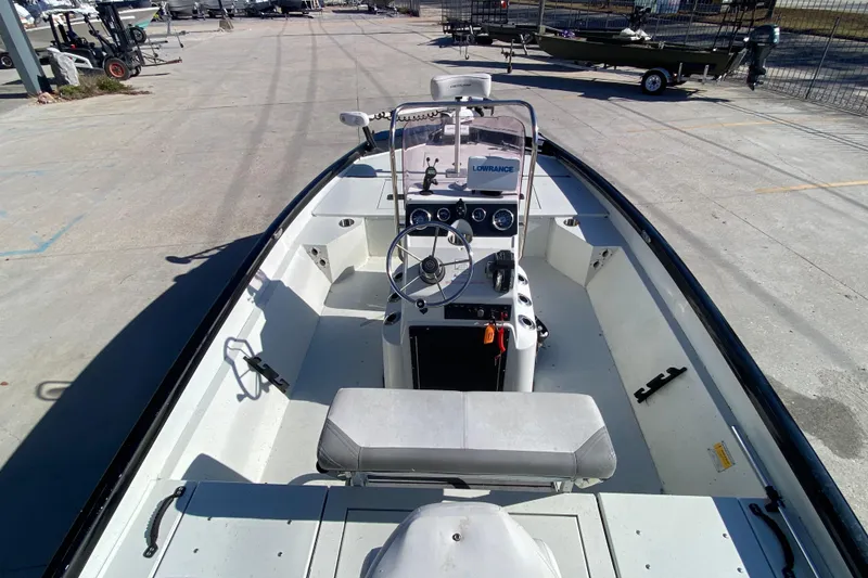 Slide: The Image of 2019 Crestliner 1800 Bay boat interior with steering console and seating, parked outdoors. - 19