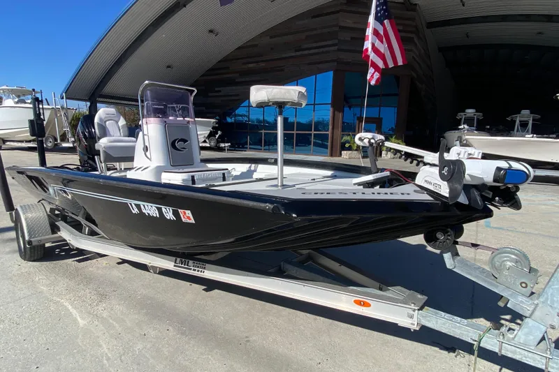 Slide: The Image of 2019 Crestliner 1800 Bay boat on trailer, parked outdoors with American flag. - 8