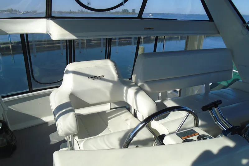 Slide: The Image of 2004 Carver 356 Motor Yacht helm with white seating and steering wheel, overlooking water. - 13