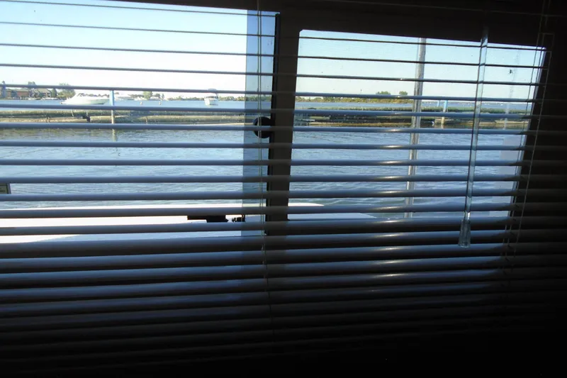 Slide: The Image of Blinds partially open, revealing a serene waterfront view from a 2004 Carver 356 Motor Yacht. - 47