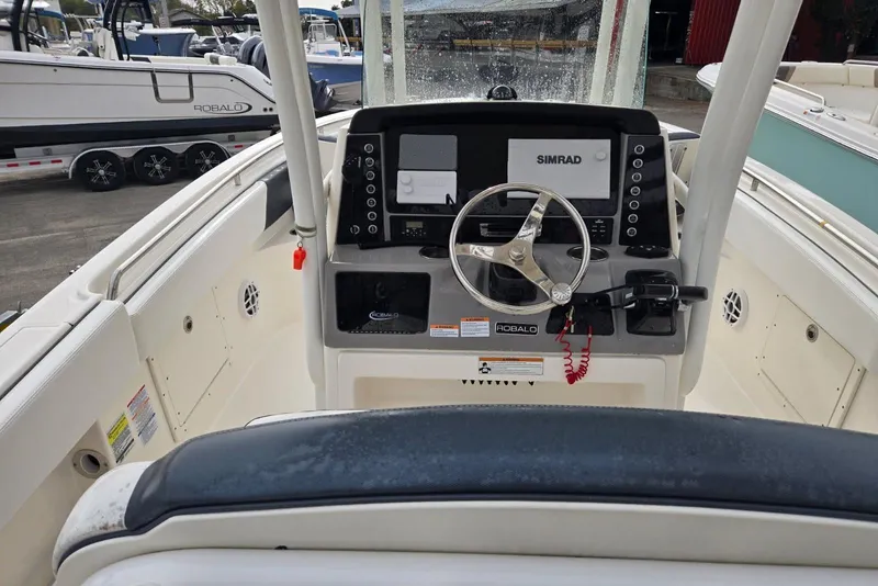 Slide: The Image of 2021 Robalo R242 Center Console boat dashboard with steering wheel and Simrad display. - 4