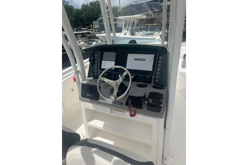 Slide: The Image of 2021 Robalo R242 Center Console boat dashboard with Simrad display and steering wheel. - 6