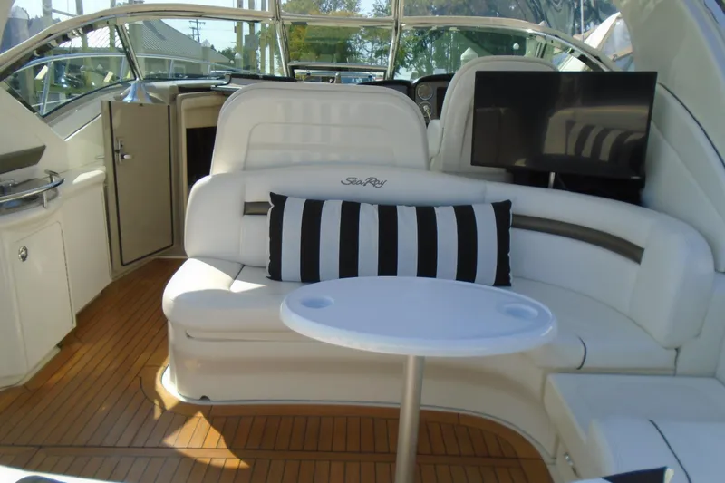 Slide: The Image of 2007 Sea Ray 40 Sundancer interior with white seating, striped pillow, and mounted TV. - 10
