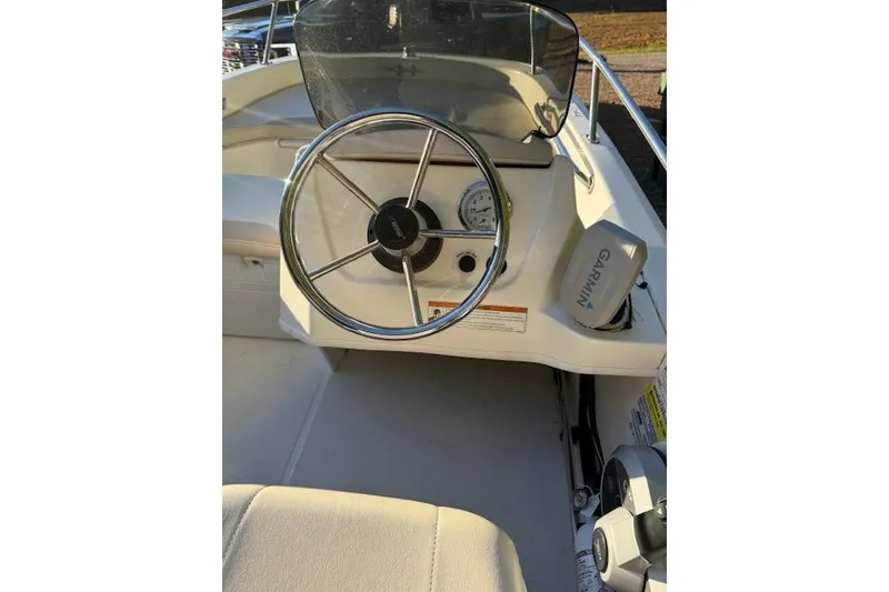 Slide: The Image of 2021 Boston Whaler 130 Super Sport boat dashboard with steering wheel and Garmin device. - 11