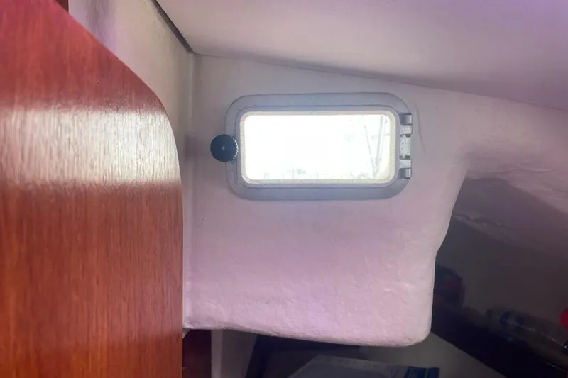 Slide: The Image of Interior view of 1984 Beneteau First 38.5 sailboat with small window and wooden paneling. - 20