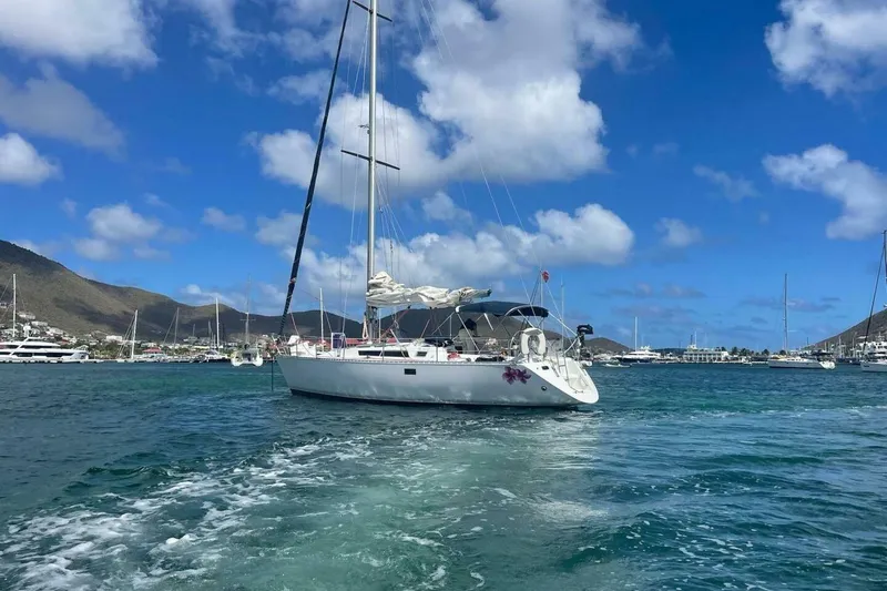 Slide: The Image of 1984 Beneteau First 38.5 sailboat cruising in a scenic marina under a clear blue sky. - 23