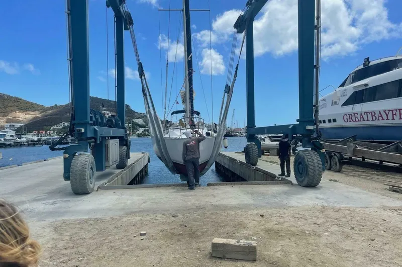 Slide: The Image of 1984 Beneteau First 38.5 sailboat being lifted at a marina with blue skies. - 3