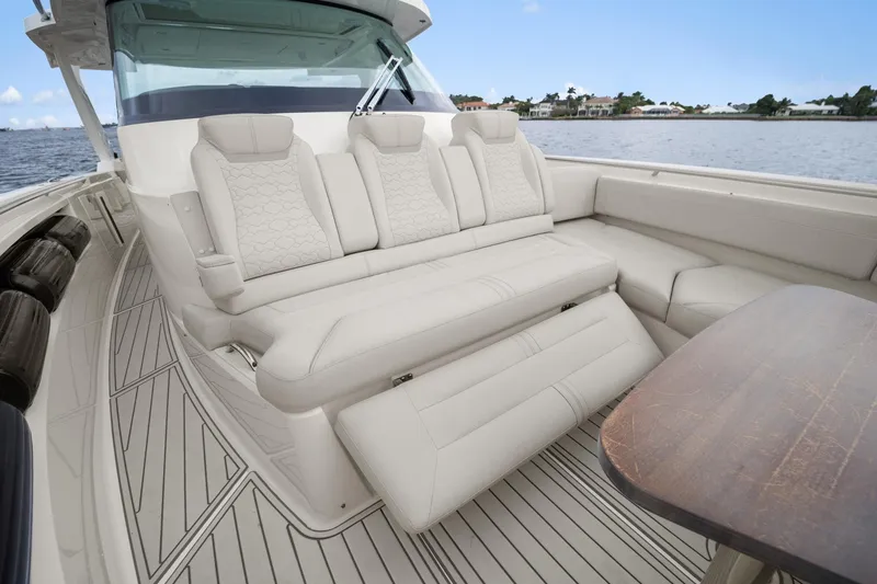 Slide: The Image of 2022 Tiara Sport 43 LS luxury boat interior with plush seating and wooden table. - 12