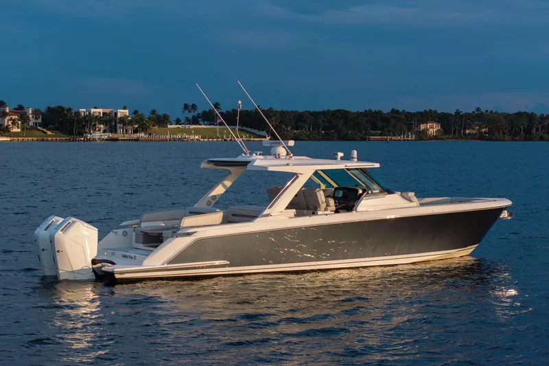 Slide: The Image of 2022 Tiara Sport 43 LS luxury boat on calm water at sunset. - 2