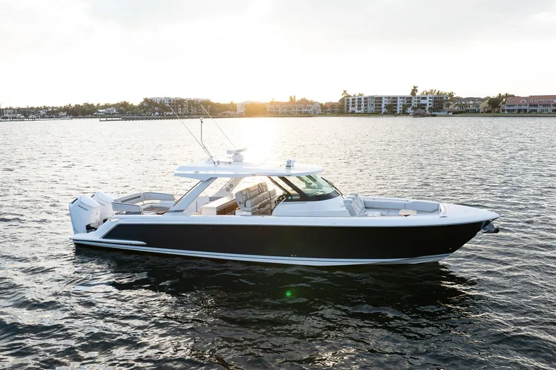 Slide: The Image of 2022 Tiara Sport 43 LS luxury boat on calm water at sunset. - 34