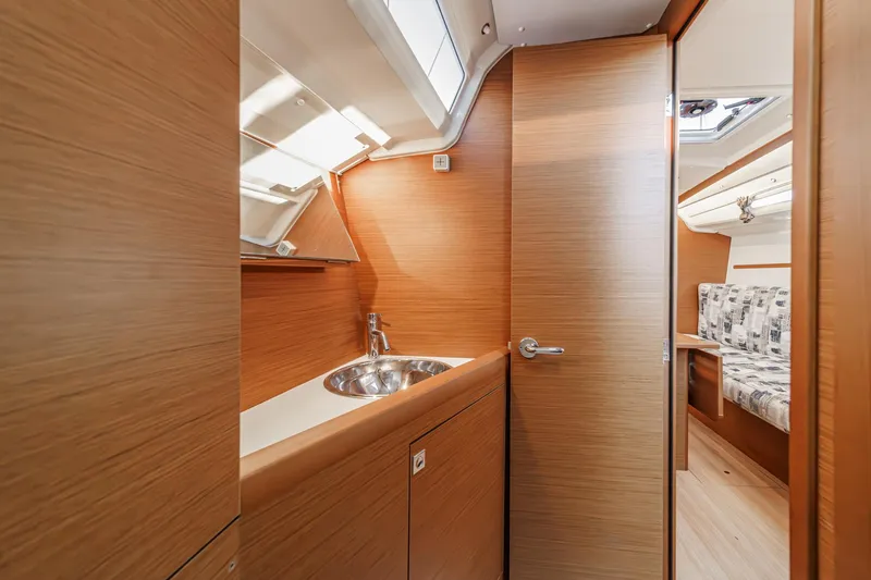 Slide: The Image of 2022 Jeanneau Sun Odyssey 349 interior with wooden cabinetry and compact sink. - 28
