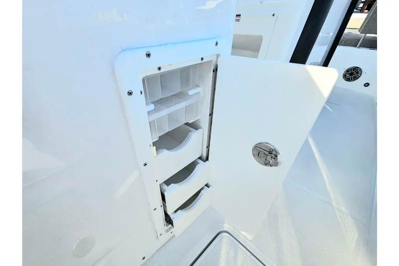 Slide: The Image of Storage compartment on 2026 Sea Hunt Ultra 285 SE boat, featuring open door and shelves. - 12