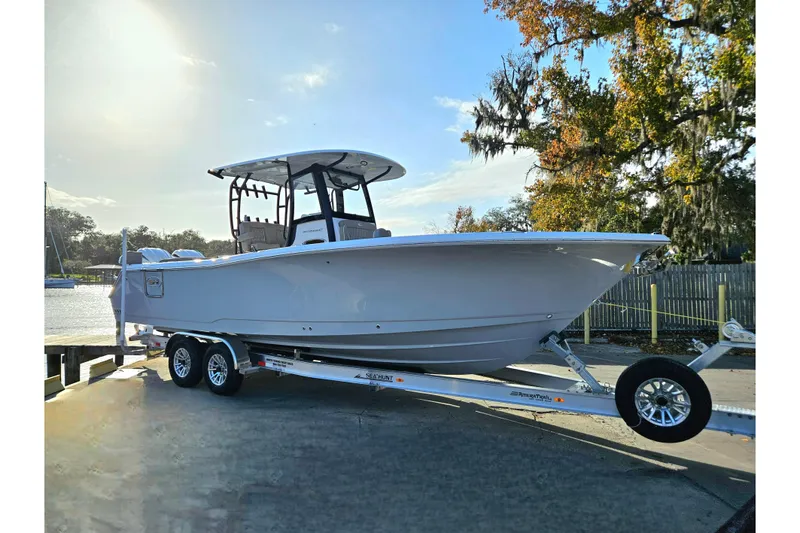 Slide: The Image of 2026 Sea Hunt Ultra 285 SE boat on trailer, parked near water and trees. - 3