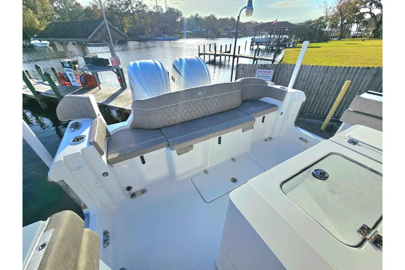 Slide: The Image of 2026 Sea Hunt Ultra 285 SE boat interior with seating, docked by a scenic waterfront. - 7