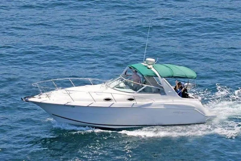 Slide: The Image of 2000 Monterey 302 Cruiser boat navigating on open water with green canopy. - 0
