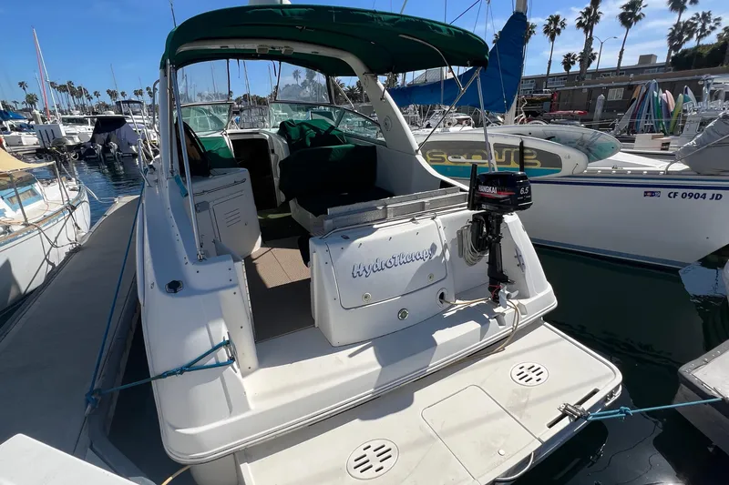 Slide: The Image of 2000 Monterey 302 Cruiser docked at marina, featuring green canopy and outboard motor. - 11