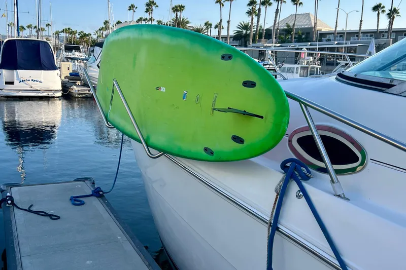 Slide: The Image of 2000 Monterey 302 Cruiser with green surfboard docked at marina. - 13