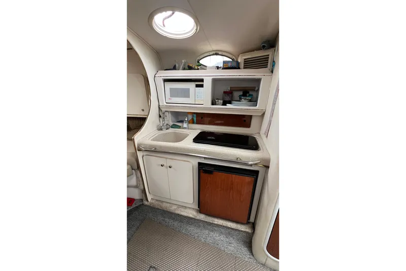 Slide: The Image of Compact kitchen area in a 2000 Monterey 302 Cruiser boat, featuring a sink, microwave, and mini-fridge. - 34
