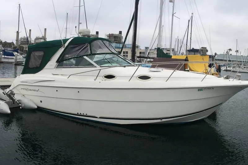 Slide: The Image of 2000 Monterey 302 Cruiser boat docked in marina, featuring sleek design and green canopy. - 4