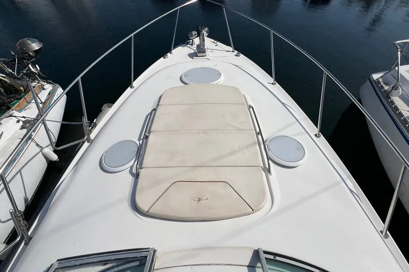 Slide: The Image of 2000 Monterey 302 Cruiser boat deck with sun pad and railing, docked on calm water. - 9