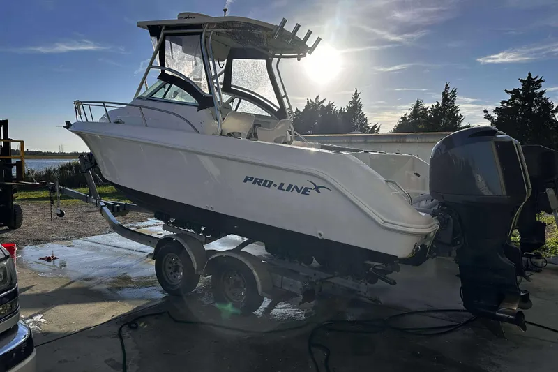 Slide: The Image of 2003 Pro-Line 23 WA boat on trailer, parked outdoors under a clear sky. - 2