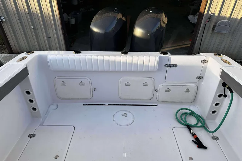 Slide: The Image of 2003 Pro-Line 23 WA boat deck with storage compartments and green hose. - 7