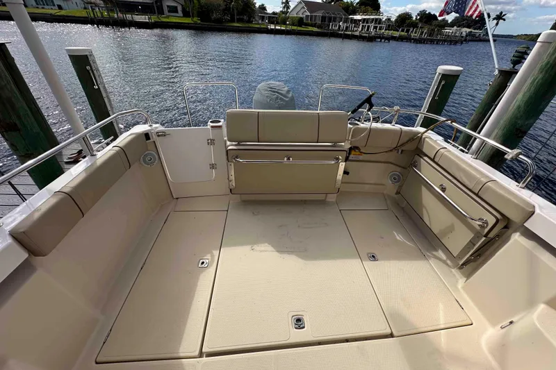 Slide: The Image of 2020 Ranger Tugs R-23 boat deck with seating, docked by a scenic waterfront. - 11