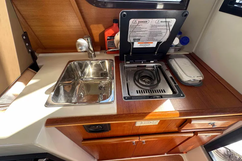 Slide: The Image of Compact kitchen area in a 2020 Ranger Tugs R-23 boat, featuring a sink and stove. - 17