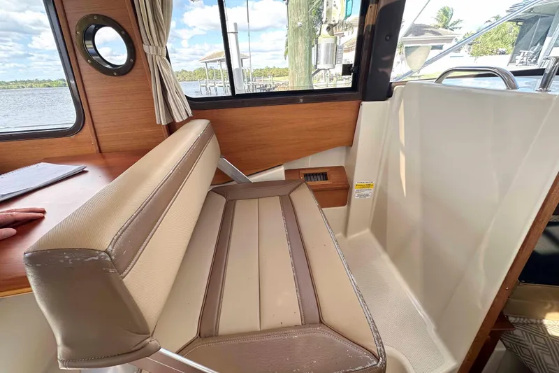 Slide: The Image of 2020 Ranger Tugs R-23 interior with beige seating and wood accents, overlooking water. - 21