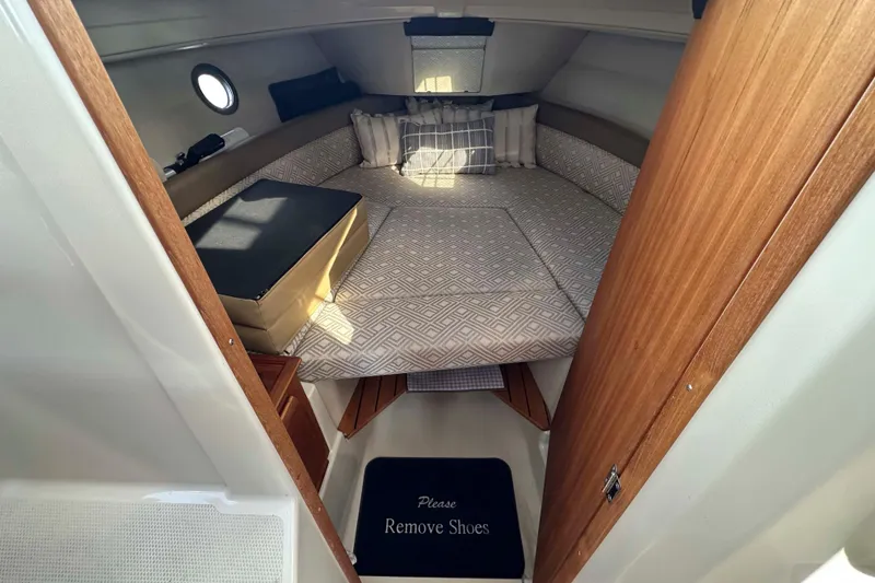 Slide: The Image of 2020 Ranger Tugs R-23 cabin interior with cozy bed and "Please Remove Shoes" mat. - 22