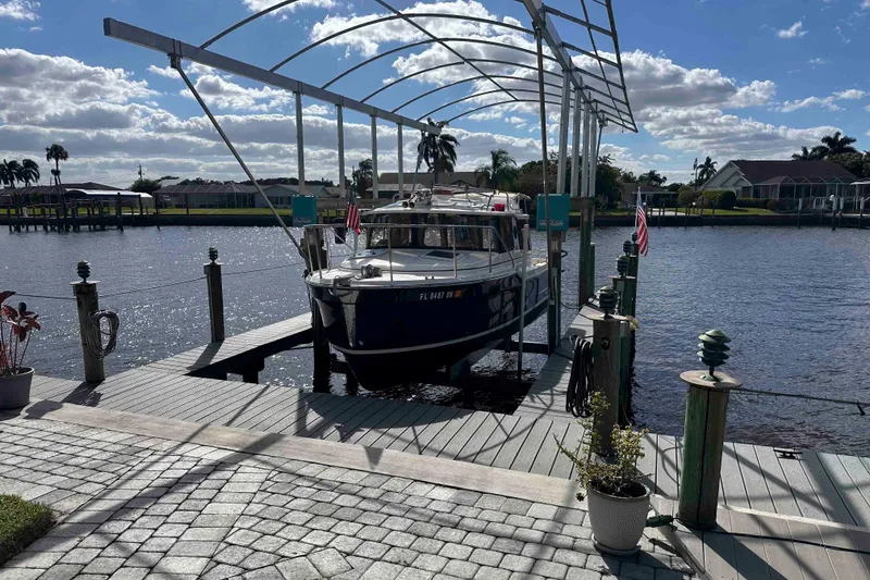Slide: The Image of 2020 Ranger Tugs R-23 boat docked on a sunny waterfront with American flags. - 5
