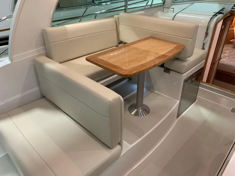 Slide: The Image of 2027 Back Cove 34O Hardtop Express interior with beige seating and wooden table. - 9