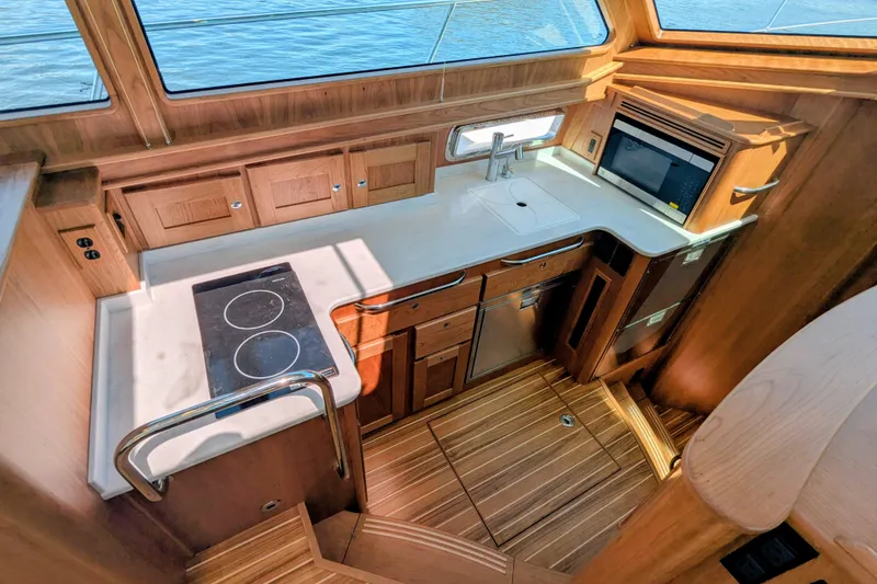 Slide: The Image of 2026 Sabre 45 Salon Express yacht kitchen with modern appliances and wooden cabinetry. - 17
