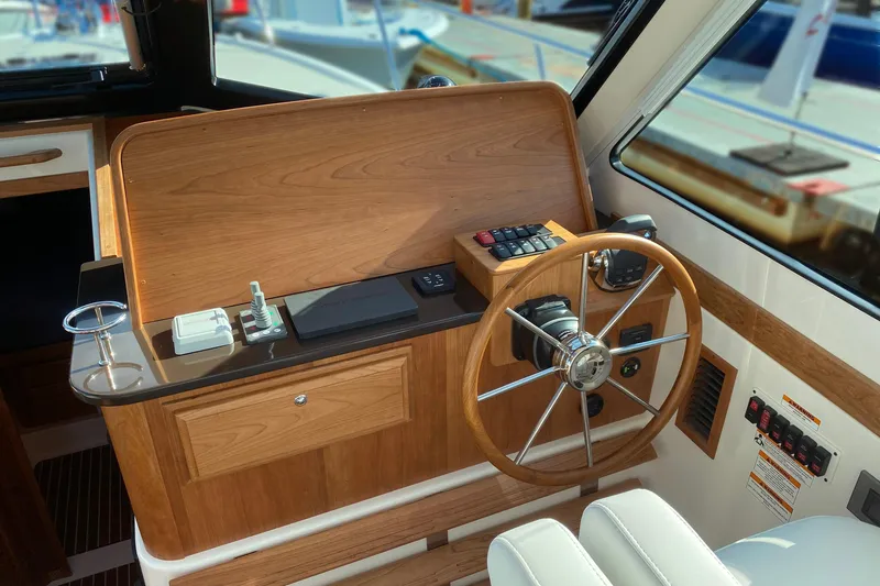 Slide: The Image of Helm station of 2027 Back Cove 372 boat with wooden finish and modern controls. - 14