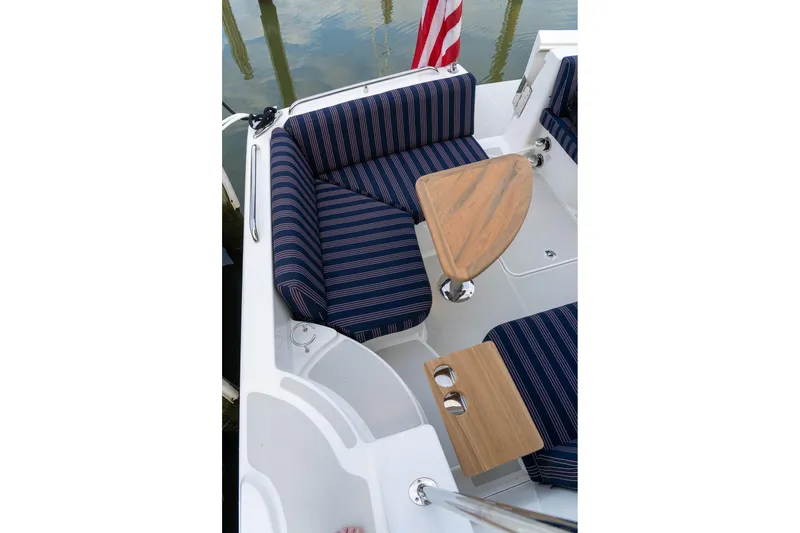 Slide: The Image of Cozy seating area on 2027 Back Cove 372 boat with striped cushions and wooden tables. - 4