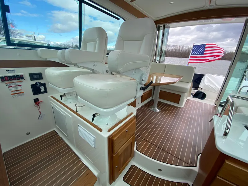 Slide: The Image of 2025 Back Cove 37 Hardtop Express interior with plush seating and American flag in view. - 6