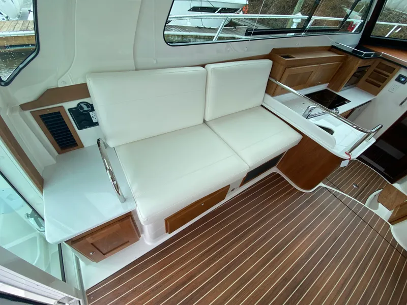 Slide: The Image of 2025 Back Cove 37 Hardtop Express interior with white seating and wood accents. - 5
