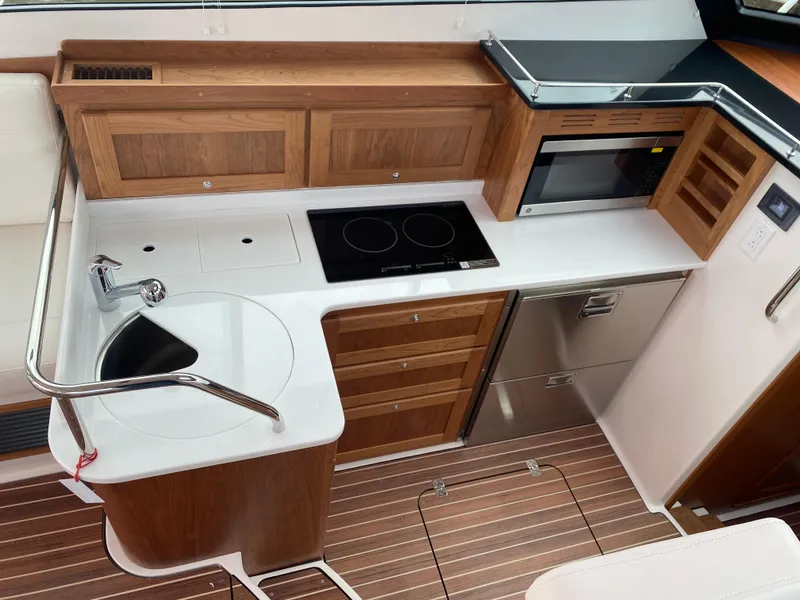 Slide: The Image of 2025 Back Cove 37 Hardtop Express galley with modern appliances and wooden cabinetry. - 6